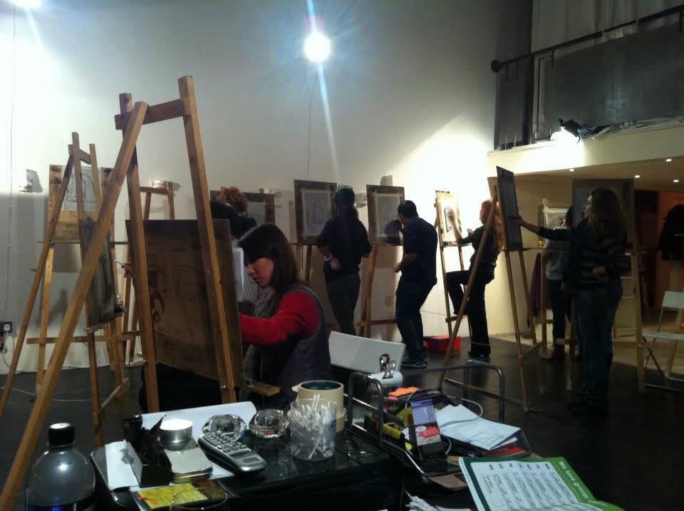Students drawing at tall easels during a busy atelier class