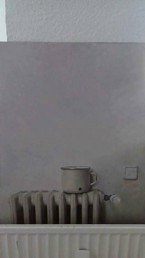 Quiet atelier detail with an enamel cup resting on a radiator