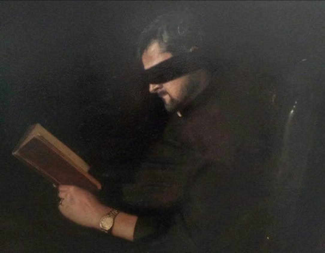 Dark figurative painting of a person reading